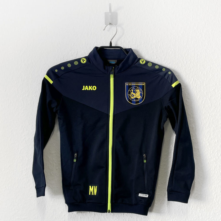 Die Jako Kinder Trainingsjacke mit Vereinslogo in Farbe