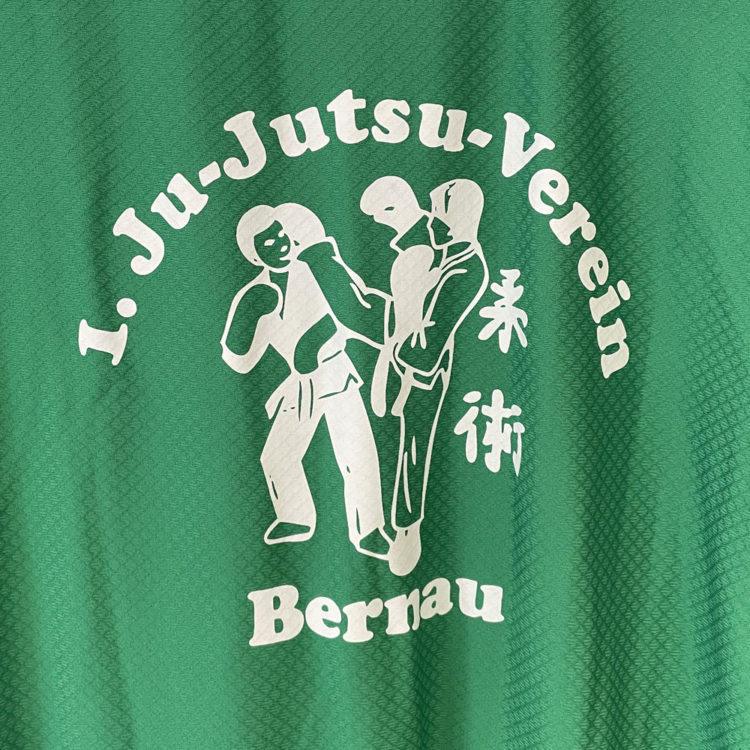 weißes Ju-Jutsu Logo auf den grünen Sportjacken