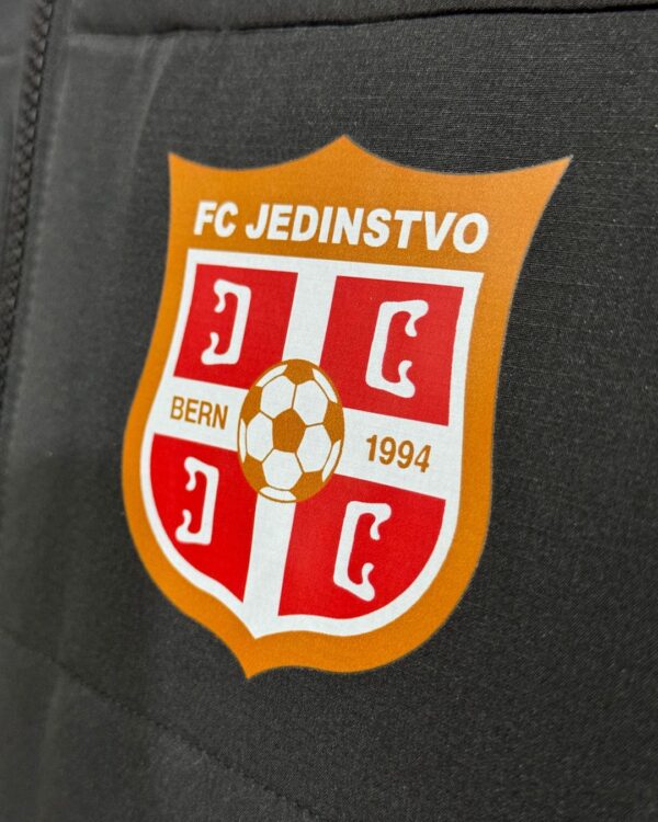 farbiges Vereinswappen auf Stadionjacken von Jako in schwarz
