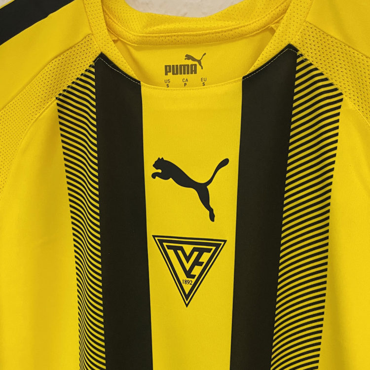 gelbe gestreifte Puma Trikots mit Club Logo in schwarz auf der Brust