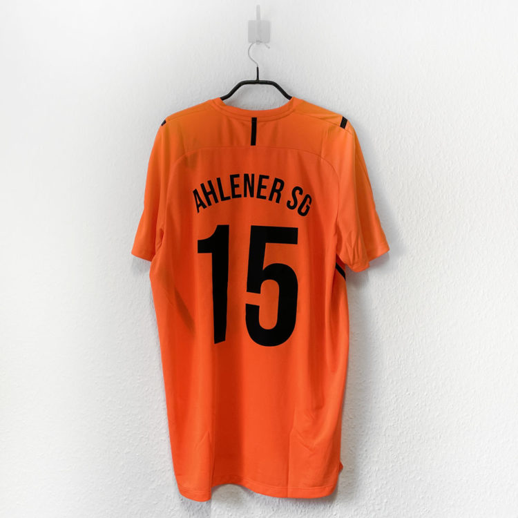 orange Trikot mit schwarzer Bedruckung des Vereinsnamens und der Rückennummer