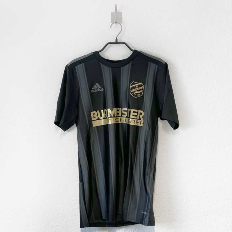 Vereinslogo und Sponsor in gold auf schwarz grauen adidas Trikots