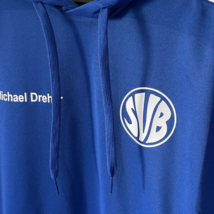 die weiße Vereinslogo Bedruckung auf dem Hoodie von adidas